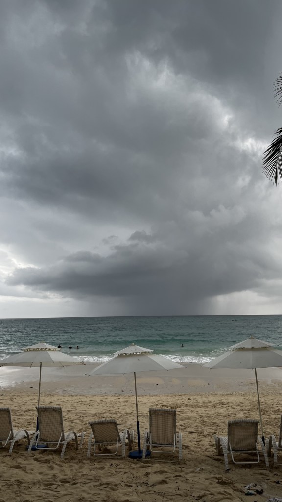 A photo of Boracay beach on Station 3. A number of empty seats, a dark and gloomy skies, and a couple of daredevils swimming from a far.