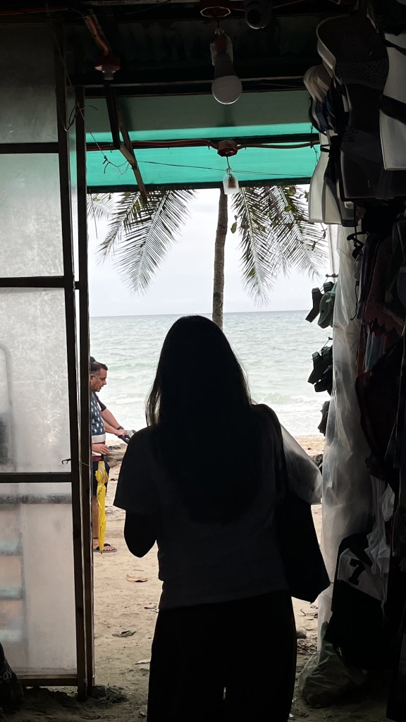 A silhouette of a woman looking outside of an anik-anik store.