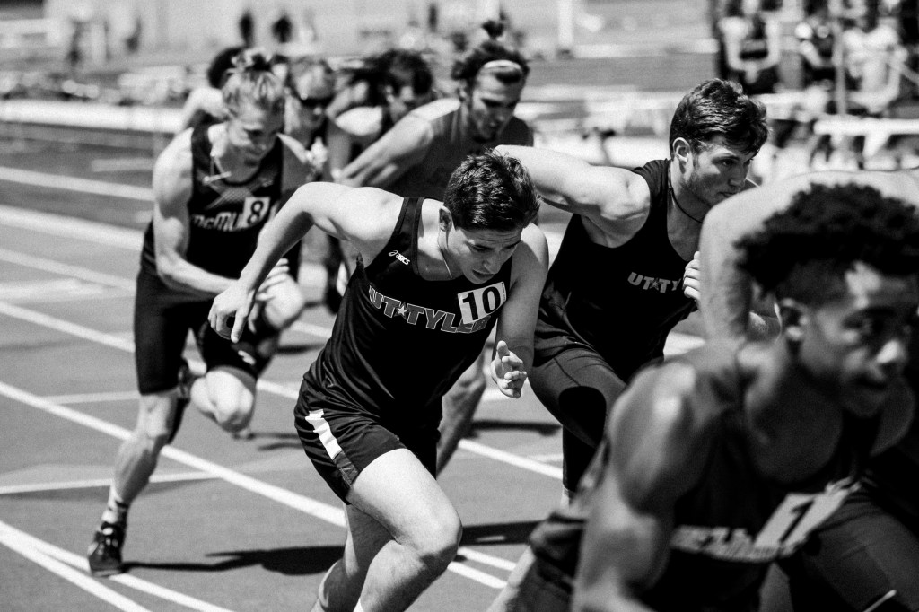 Runners in a competitive race sprinting forward at the starting line, displaying determination and focus.