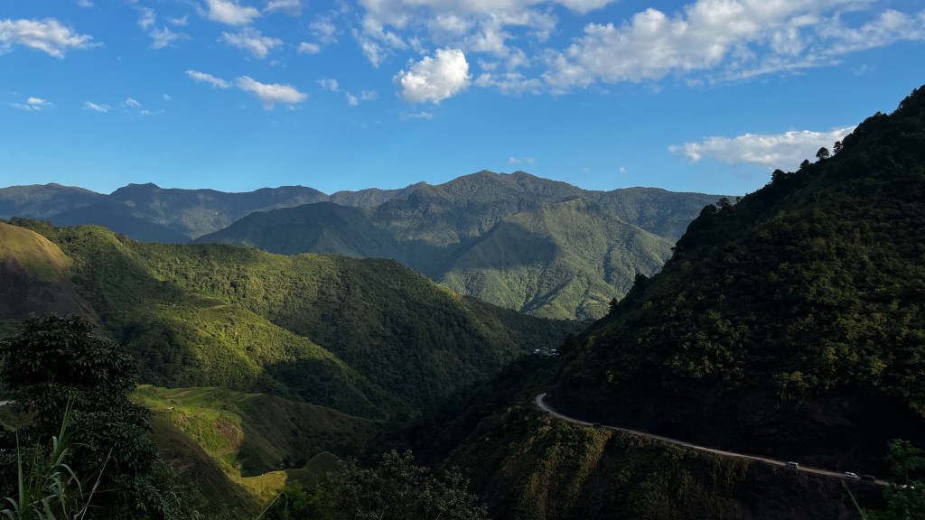 A breathtaking view of the mountain ranges along the winding road to Buscalan Village in Kalinga, Philippines, surrounded by lush greenery.