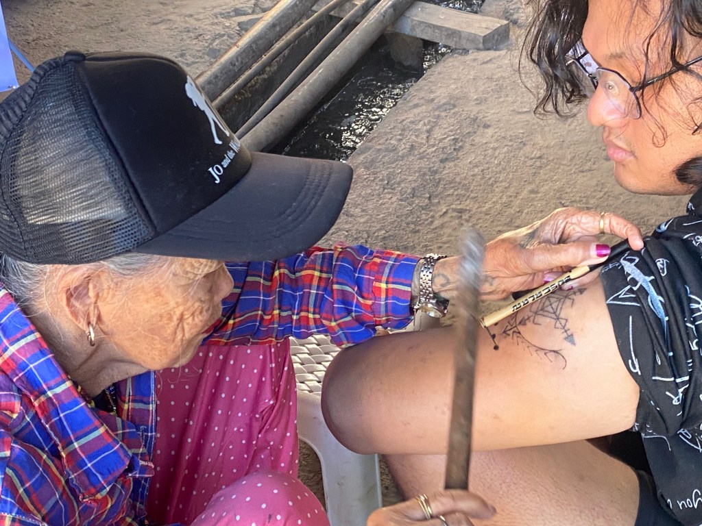 Receiving a traditional Kalinga tattoo from Whang-Od, the legendary mambabatok of Buscalan Village, using the ancient batok hand-tap method.