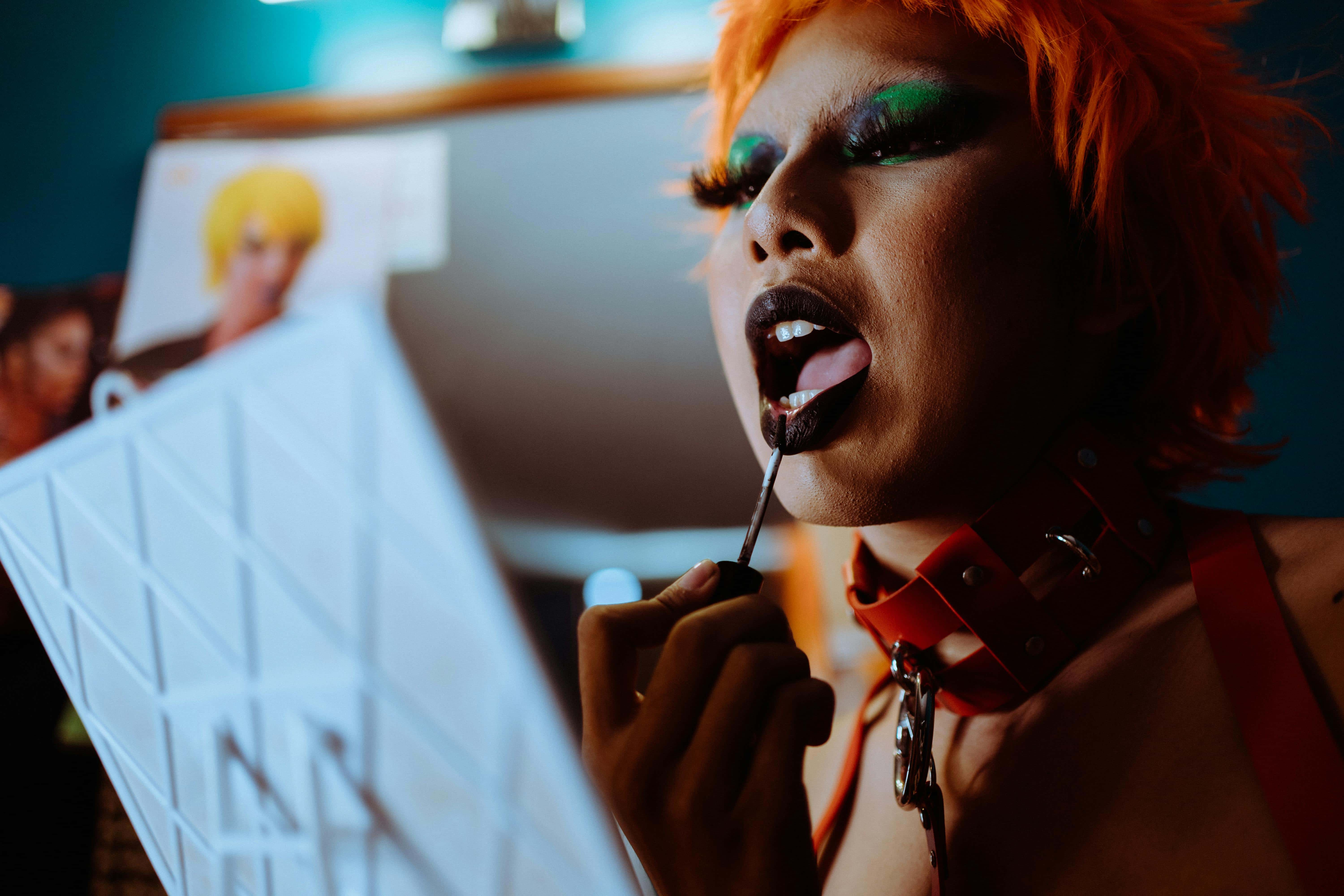 Close-up of a person wearing dramatic makeup and applying dark lipstick, symbolizing self-expression and reclaiming emotional space.