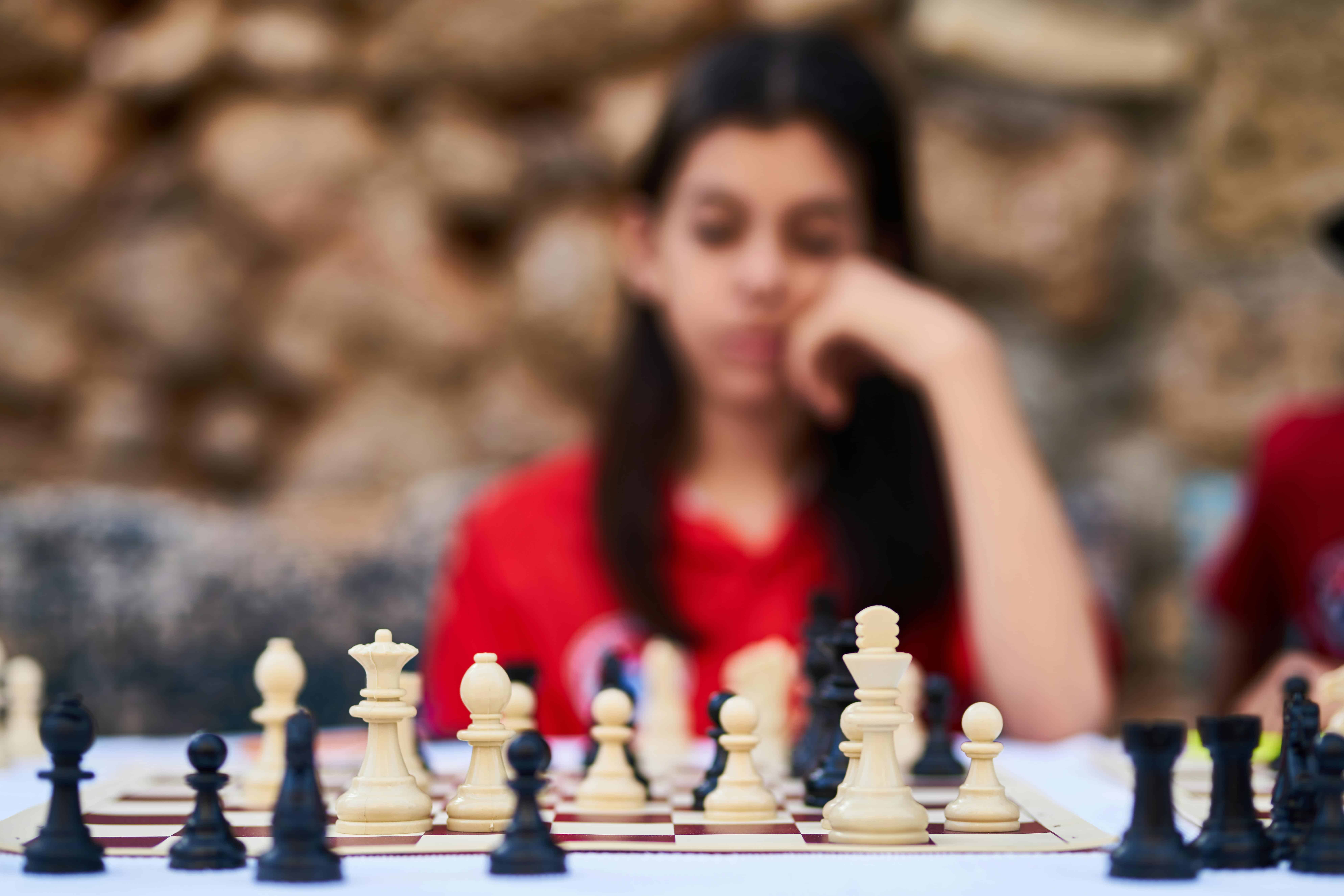 A person sitting in front of a chessboard, deep in thought as they consider their next move.