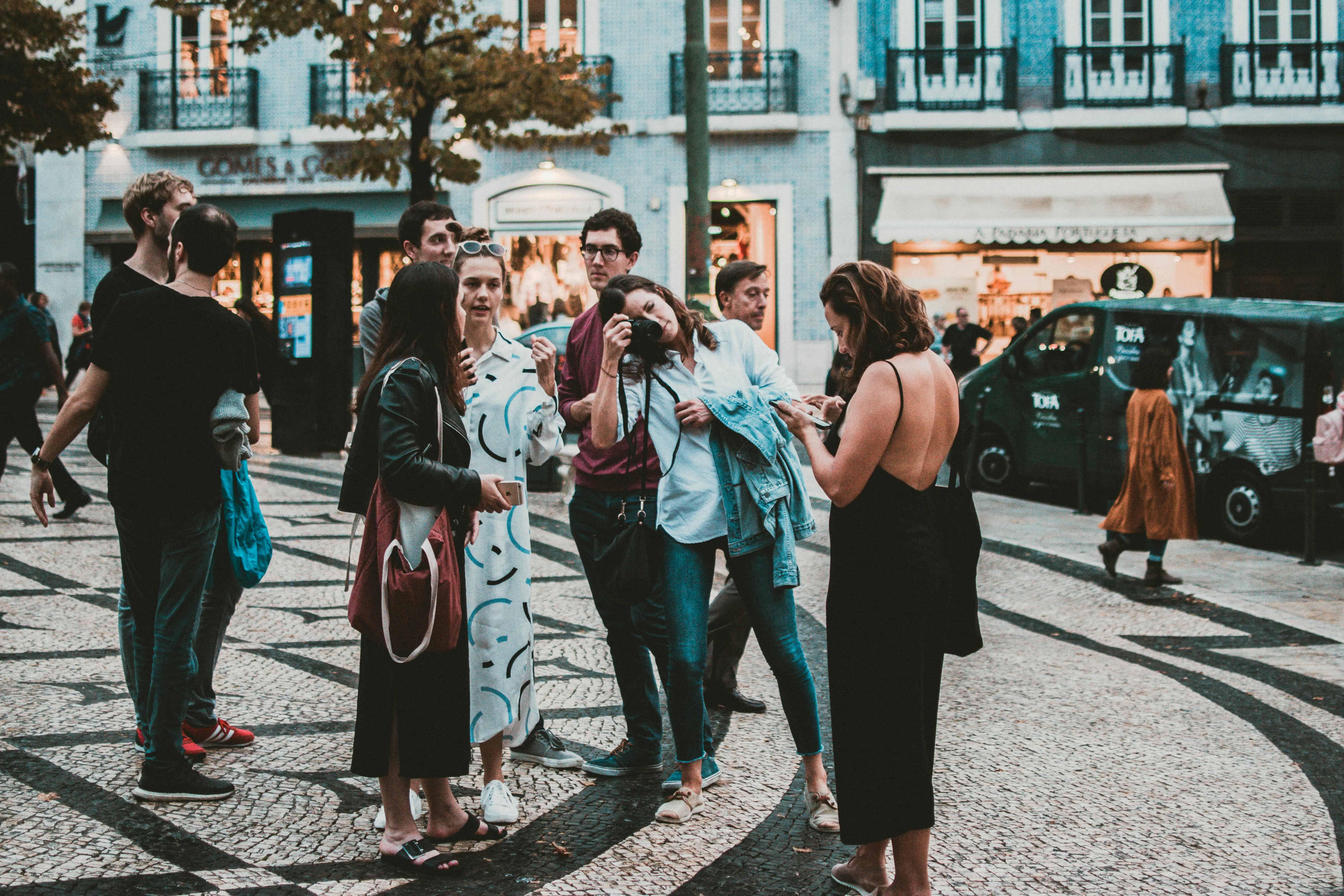 A small group of travelers standing and talking in a city square during a guided tour