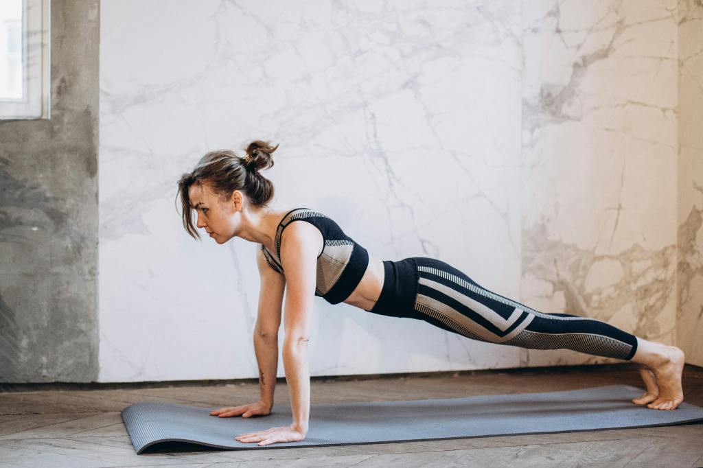 Person holding a plank position at home, representing the challenge of sustaining progress and motivation in home workouts over time.