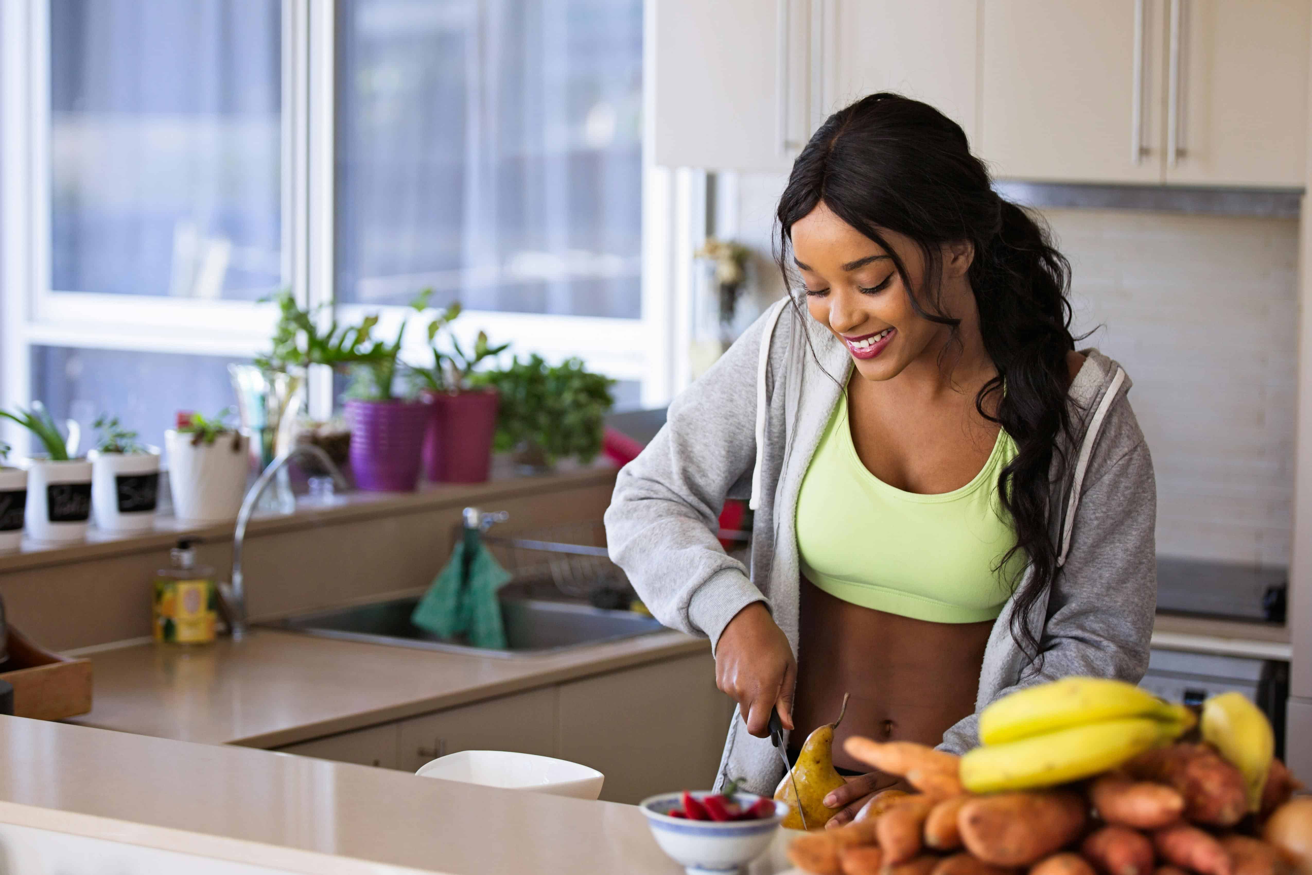 A woman preparing fruit in a bright kitchen, representing simple daily routines that reduce friction and save time for responsible adults.